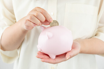 貯金箱にお金を入れる女性の手元01