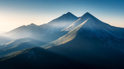 Fototapeta premium Majestic mountain peaks with morning sun rays breaking through the clouds.