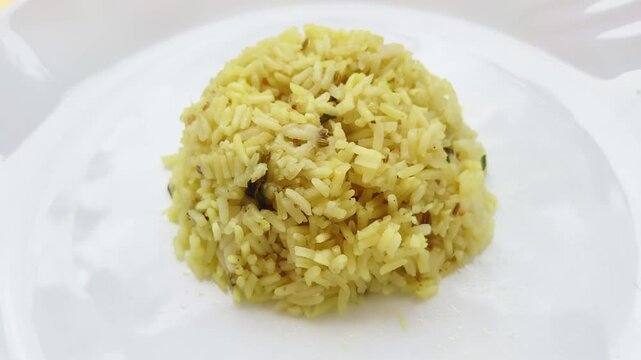 Cooked basmati rice biriyani served and isolated on a white plate background with copy space. Beautiful rotating closeup macro 4k top view of popular dish, food or cuisine.