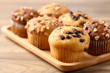 Vanilla chocolate chips muffin and chocolate almond muffin on wooden plate
