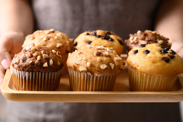 Chocolate almond muffin, Vanilla almond muffin and Vanilla chocolate chips muffin on wooden plate holding by hand