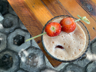 A glass of cold berry coffee with strawberries on top