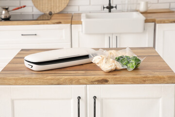 Vacuum sealer machine for food with mushrooms and broccoli in packs on kitchen table