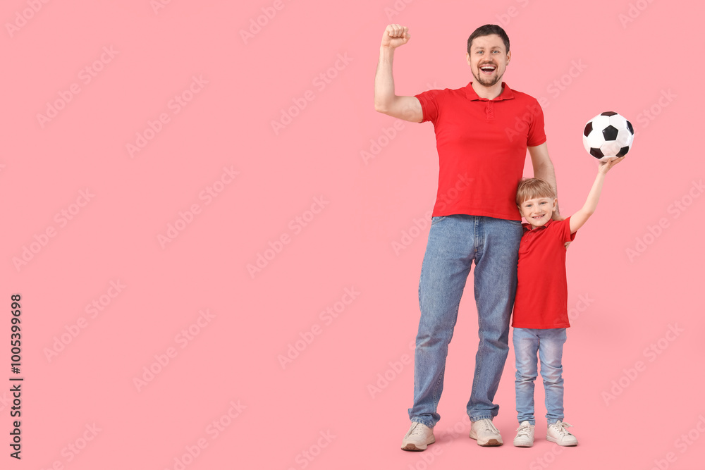 Wall mural Cute little boy and his young father with soccer ball on pink background