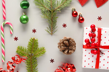 Composition with gift box, fir tree branches, candy canes and Christmas balls on light background