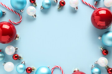 Frame made of different Christmas balls and candy canes on blue background