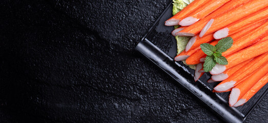 Crab sticks on black stone plate. Rustic style. Seafood delicacies. © showcake