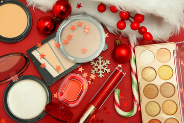 Makeup cosmetics and Christmas decor on red background. Closeup
