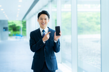 オフィスの廊下でスマホを操作するビジネスマン