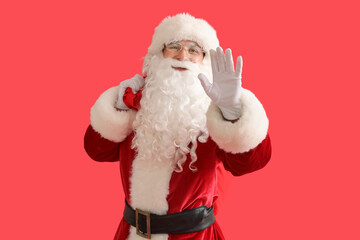 Santa Claus with bag of gifts waving hand on red background