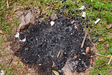 top view of burning residue isolated on grass, black grass and charcoal on green grass.
