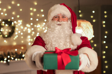 Santa Claus with gift box at home on Christmas eve