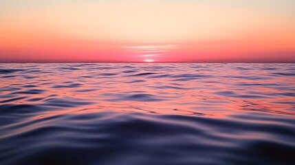 Obraz premium A vibrant pink and orange sunset reflects on the calm water of the ocean.