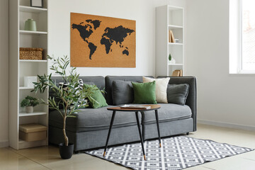 Sofa, table, shelving units and world map on white wall in living room