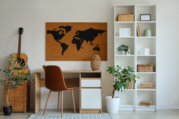 Working place with table, chair, shelving unit and world map on white wall in room