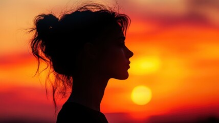 Silhouette of a woman against a vibrant sunset background.