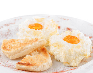 Delicious eggs in clouds with toasts on white plate being sprinkled with red pepper