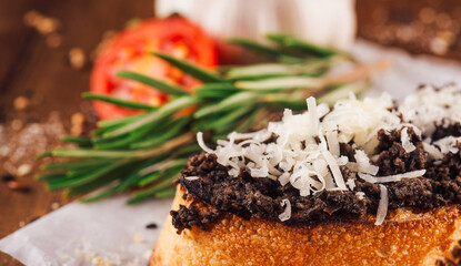 Delicious bruschetta with black truffle cream and parmesan cheese on wooden table