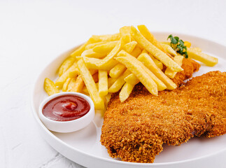 Breaded chicken breast schnitzel with french fries and ketchup on white plate
