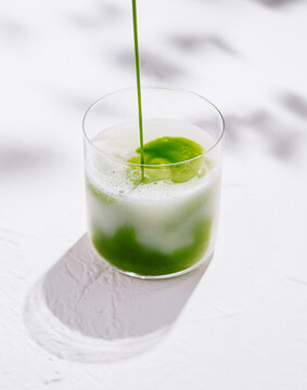 Barista pouring matcha latte in glass on white background