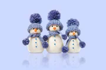 Knitted snowman in blue hat and scarf isolated on blue background. Winter fairy tale story with your own hands, hobby. Merry Christmas and New Year 2025 greeting card