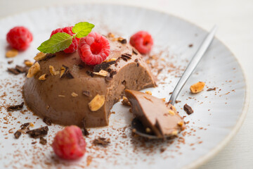 Dark chocolate flan with almonds. Decorated with cocoa powder and raspberries.