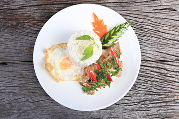 Pad kra pao moo (stir-fried thai basil with pork) and fried egg on old wood scene 