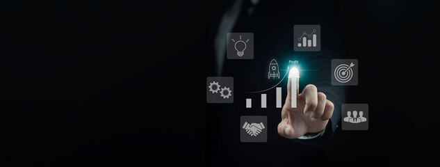 Business growth and start up concept. Businessman pointing at profit graph on dark background.