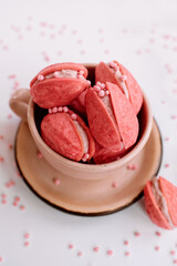 Pink walnut-shaped cookies (oreshki) in a beige cup