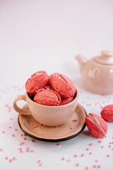 Pink walnut-shaped cookies (oreshki) in a beige cup with tea-pot