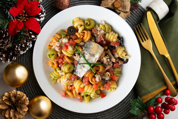 Italian pasta with sardines and black olives. Top view table with Christmas decorations.