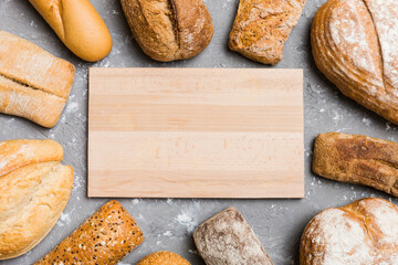 Minimalist wooden cutting board blank mockup on background of Types of homemade bread. Different...
