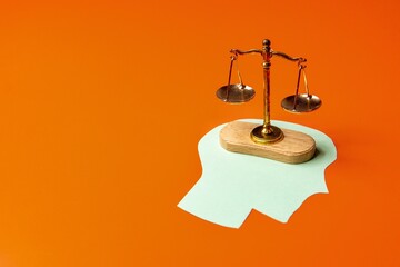 Balance scale placed on top of a green paper cutout shaped like a human head. Weighing options,...