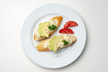 Fresh avocado and cheese spread on toasted bread garnished with cilantro and tomato