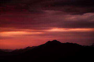 Stunning sunset over mountains with rich colors in the sky during twilight. The sky transitions with vibrant hues of orange and purple as the sun sets behind the mountains. .Breathtaking twilight view