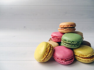 Kolorowe francuskie makaroniki ułożone w stos z dużą ilością miejsca na tekst po lewej stronie