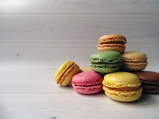 Kolorowe francuskie makaroniki ułożone w stos na białym tle z miejscem na tekst po lewej stronie