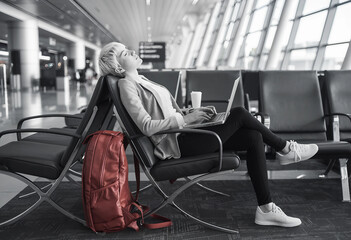 Woman Relaxing in Airport Lounge While Working on Laptop, Ready for Travel