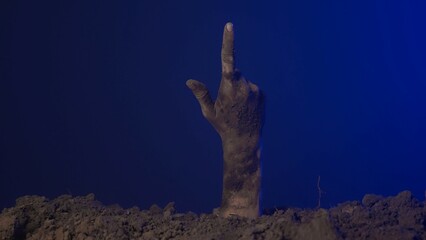 Scary dirty halloween zombie hand raising up from grave ground and pointing finger up, isolated on...