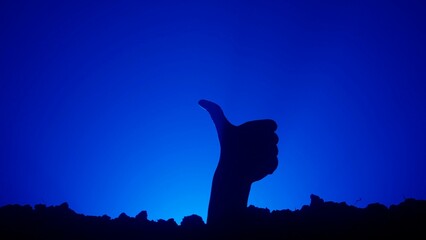 Scary dirty halloween zombie hand silhouette raising up from grave shows thumb up like gesture,...