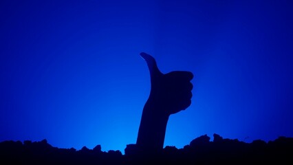 Scary dirty halloween zombie hand silhouette raising up from grave shows thumb up like gesture,...