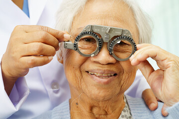 Optometrist checking Asian elderly woman ophthalmic vision eye test and using optical trial frame.
