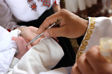 The priest performs the rite of baptism and anointing.