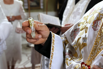 The priest performs the rite of baptism and anointing.