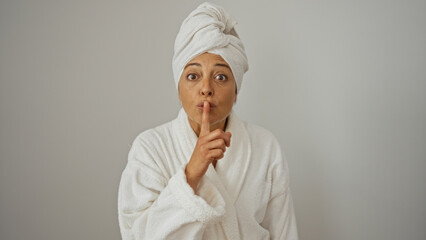 Woman in bathrobe and towel making hush gesture isolated on white background