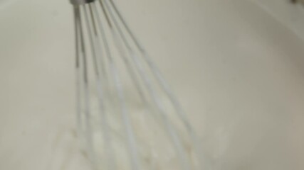 Confectioner whips eggs with sugar in a metal bowl. Cream is whipped to make a biscuit. The concept of making confectionery desserts.