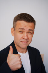 Portrait of a smiling middle-aged man in a white t-shirt and a jacket on a white background. thumbs up. photo posing. men's physical and mental health. photo for documents. half a turn 