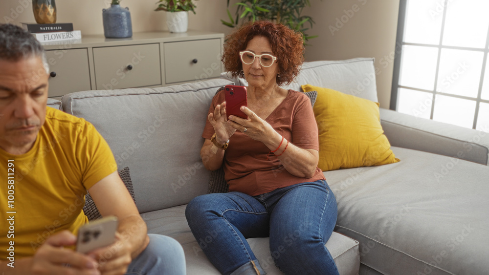 Wall mural middle-aged couple using smartphones in living room of modern apartment.