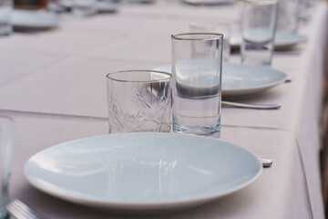 Classic tableware for table setting. plate, glasses and cutlery on a table with a linen tablecloth.