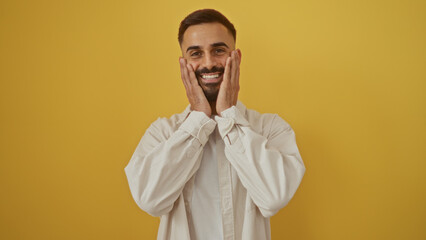 Handsome young man with a beard and a smile posing against an isolated yellow background